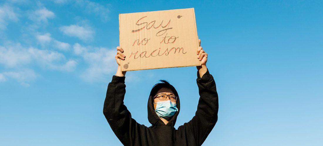 Schüler hält Schild mit Aufschrift "say no to racism"