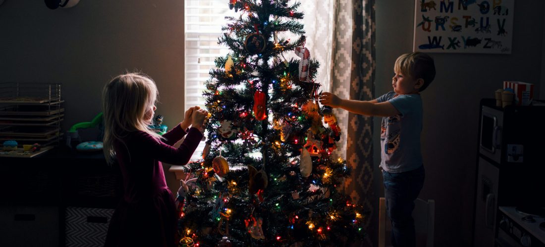 Zwei Kinder schmücken einen Weihnachtsbaum