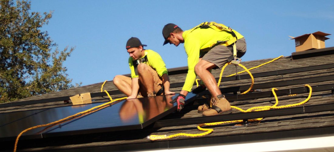 Zwei Männer bringen Solarpanels auf einem Dach an